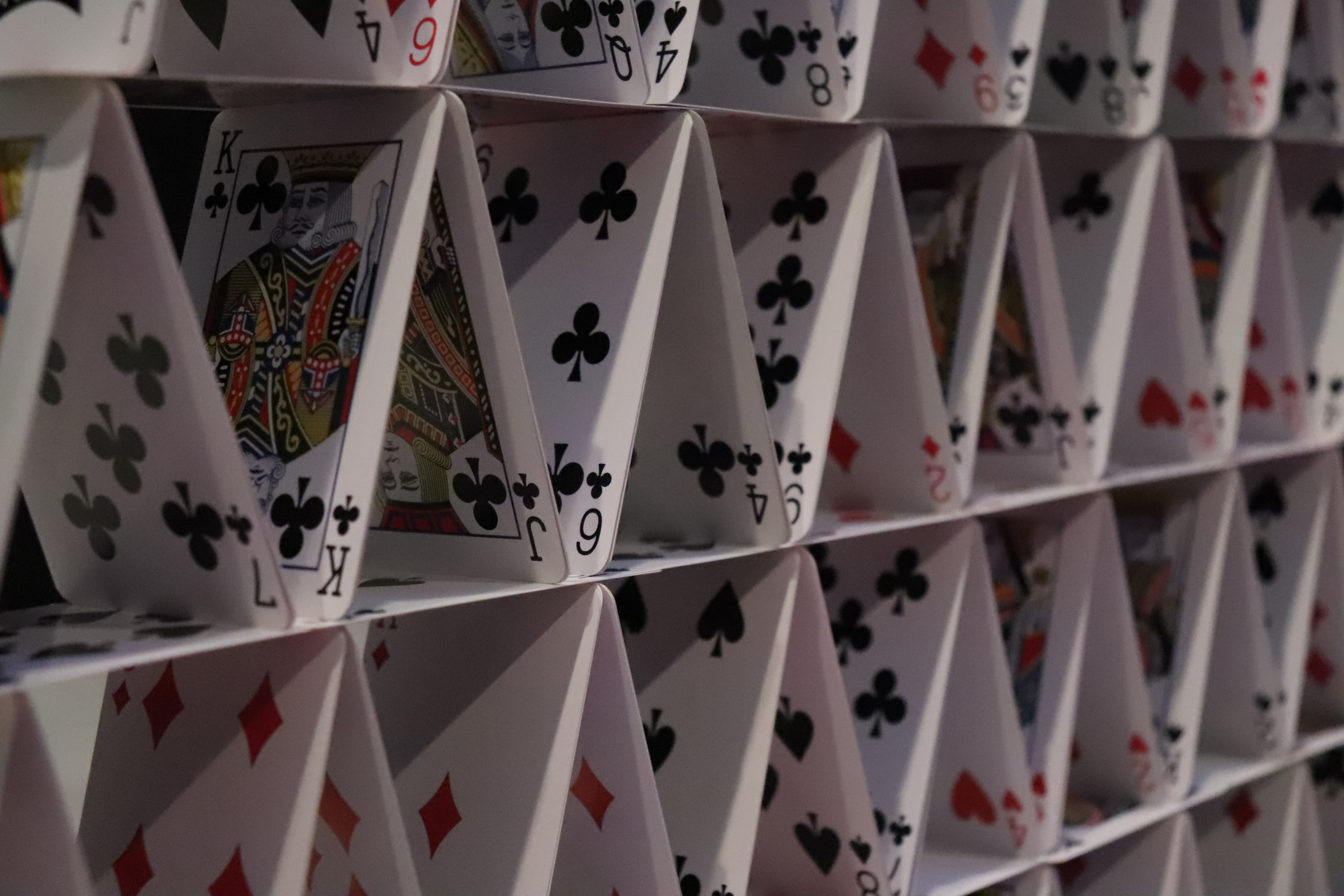 Card triangles stand in rows stacked as a house of cards.